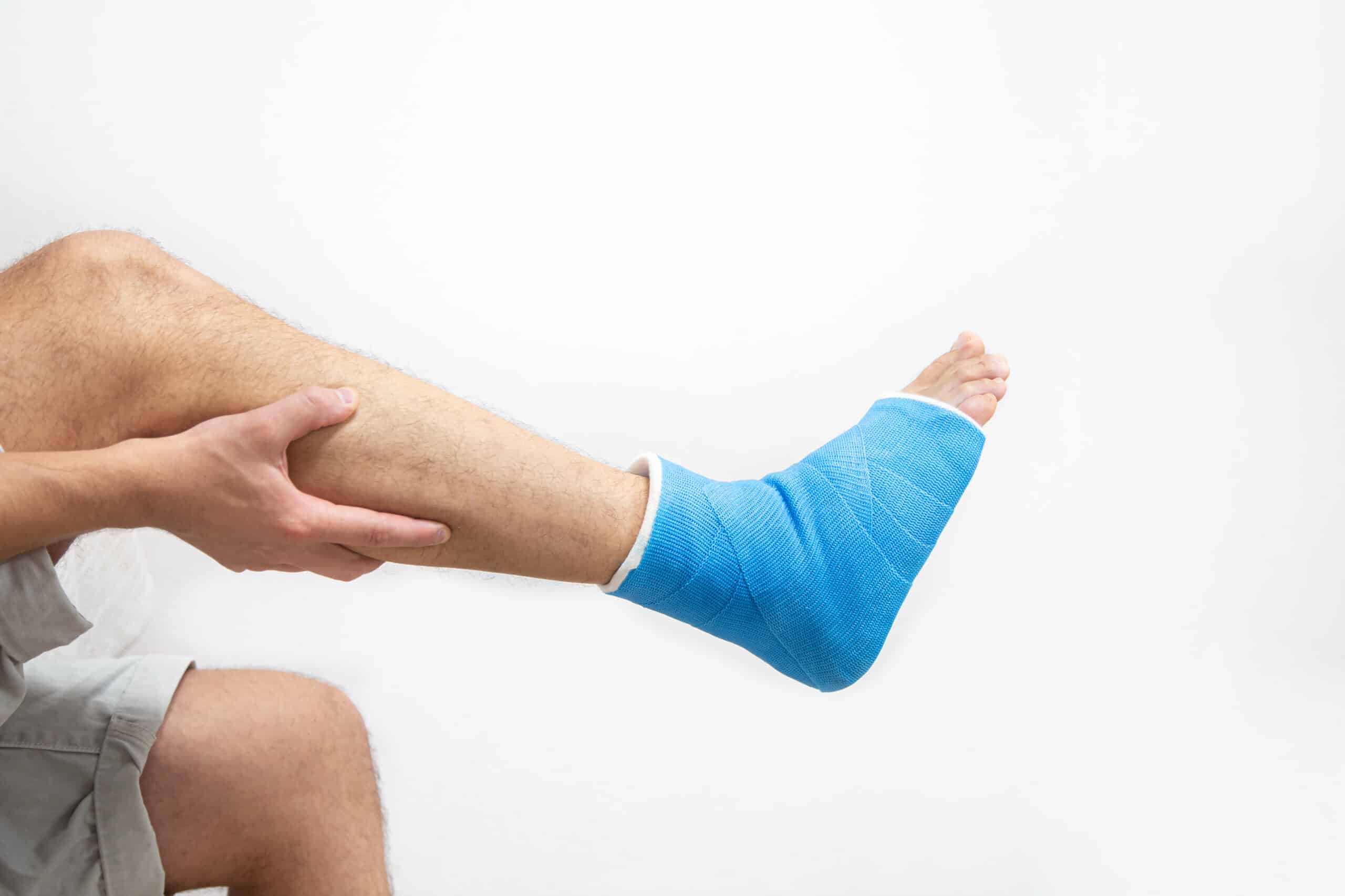 blue splint ankle bandaged leg cast male patient white background isolated sports injury concept scaled